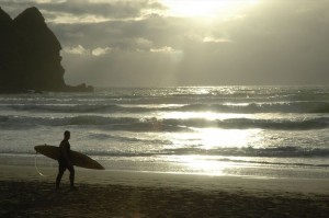 Surfař na pláži Piha Beach