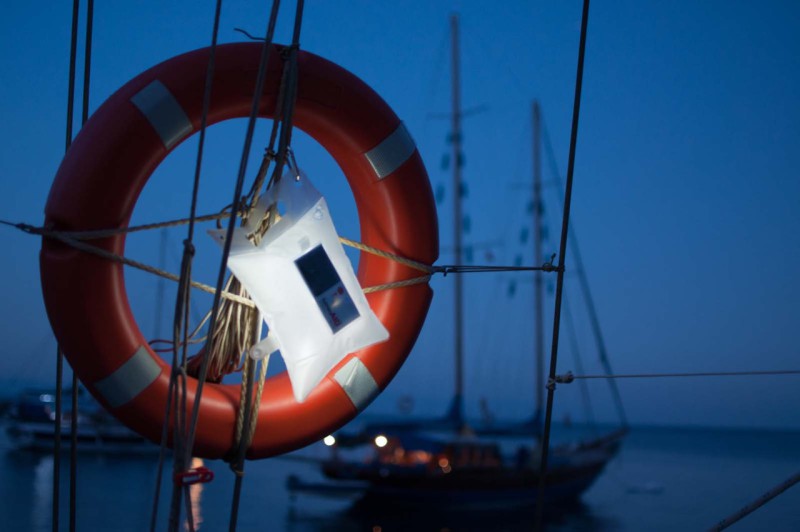 LuminAID - solární vodotěsná LED baterka v sáčku ve sbaleném stavu, zavešená na lodi.
