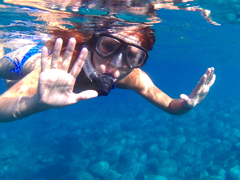 Pod vodou na ostrově La Palma. Mladá dívka v plavkách v potápečských brýlých a se šnorchlem.