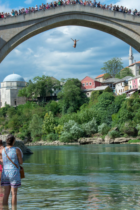 Mostar. Davy lidí na mostě i pod ním sledují odvážného skokana.