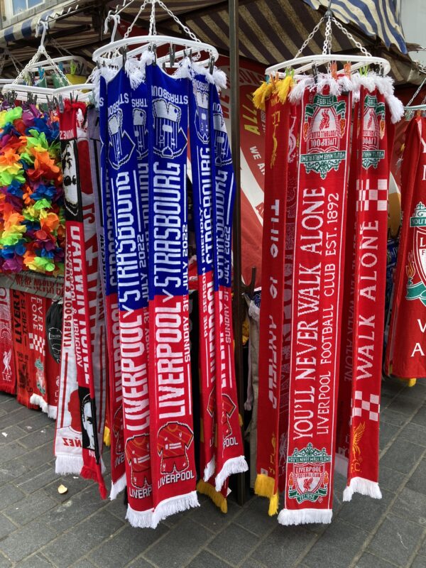 Odpoledne před zápasem FC Liverpool si můžete v ulicích města koupit šály a další fanouškovské suvenýry